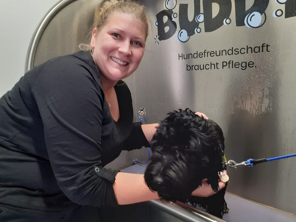 Kundin mit Hund an der Buddy-Waschwanne mit Aufschrift „Hundefreundschaft braucht Pflege“